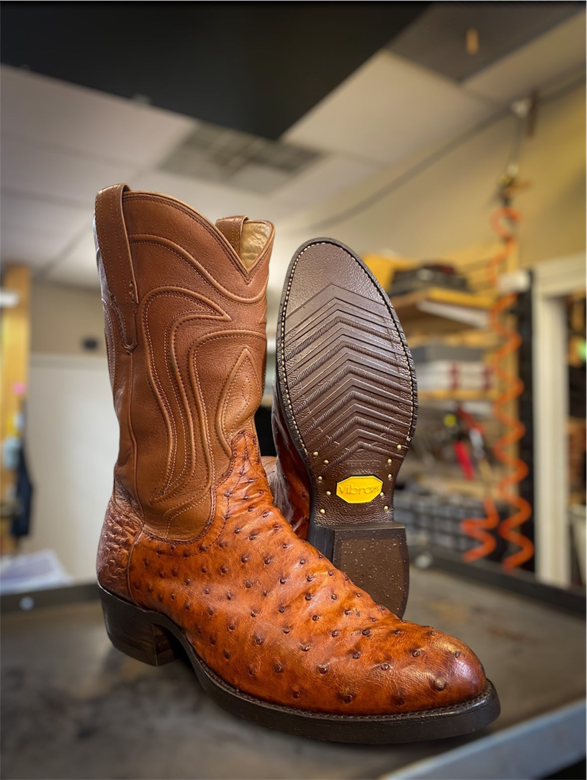 A pair of Tecovas Ostrich Skin Cowboy Boots Resoled with Brown Vibram 700 Tygum soles