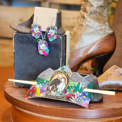 Colorful earrings and Colorful leather hair accessory displayed on a wooden stand with cowboy boots in the background