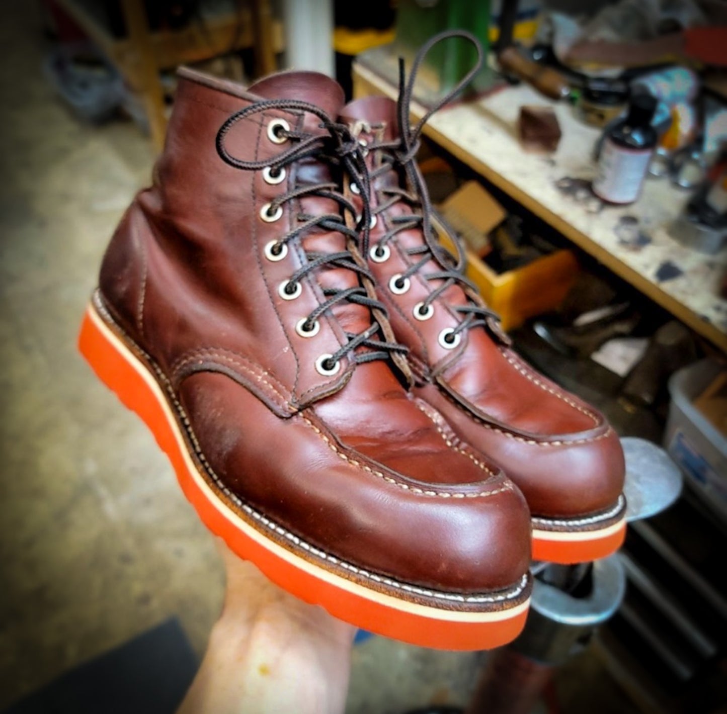 a pair of Redwing Moc-toe work boots after being repaired with new Red Vibram wedge soles at the Redwing Boot repair center