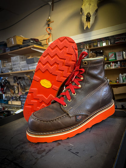 a pair of Thorogood work boots after being repaired with new Red Vibram wedge soles at the boot repair center