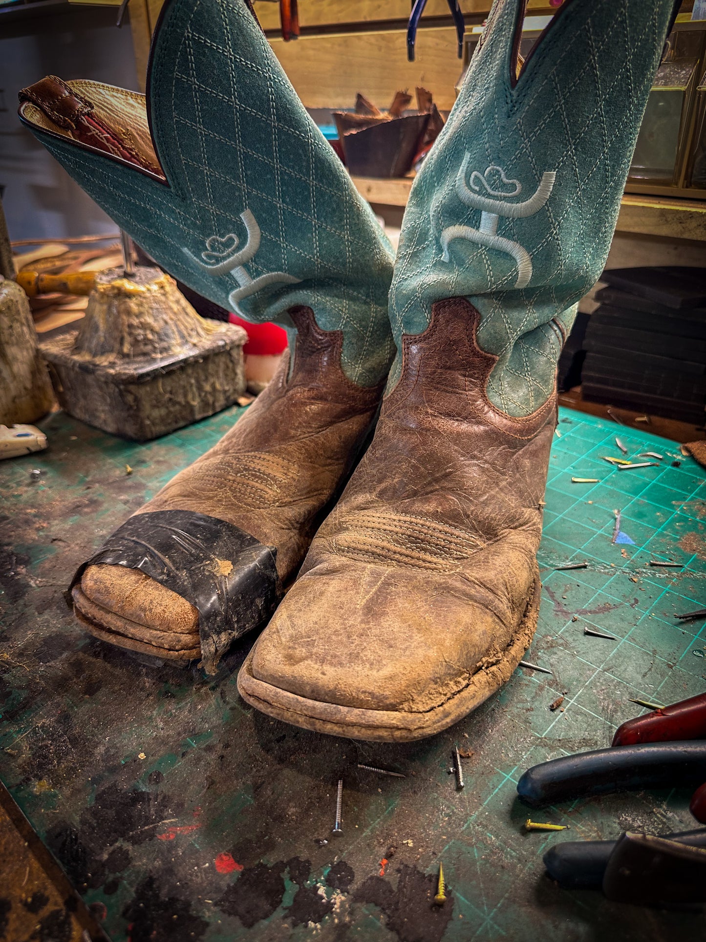 a pair of square toe boots before being repaired with new leather soles at the cowboy boot repair center