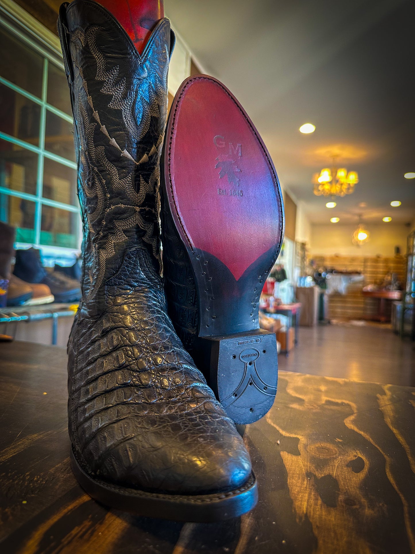 a pair of black alligator cowboy boots after being repaired with new leather soles at the cowboy boot repair center