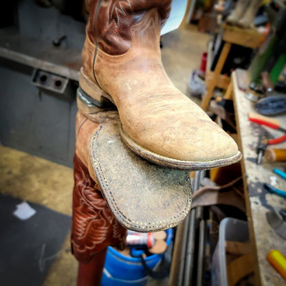 a pair of square toe boots before getting repaired with new leather soles