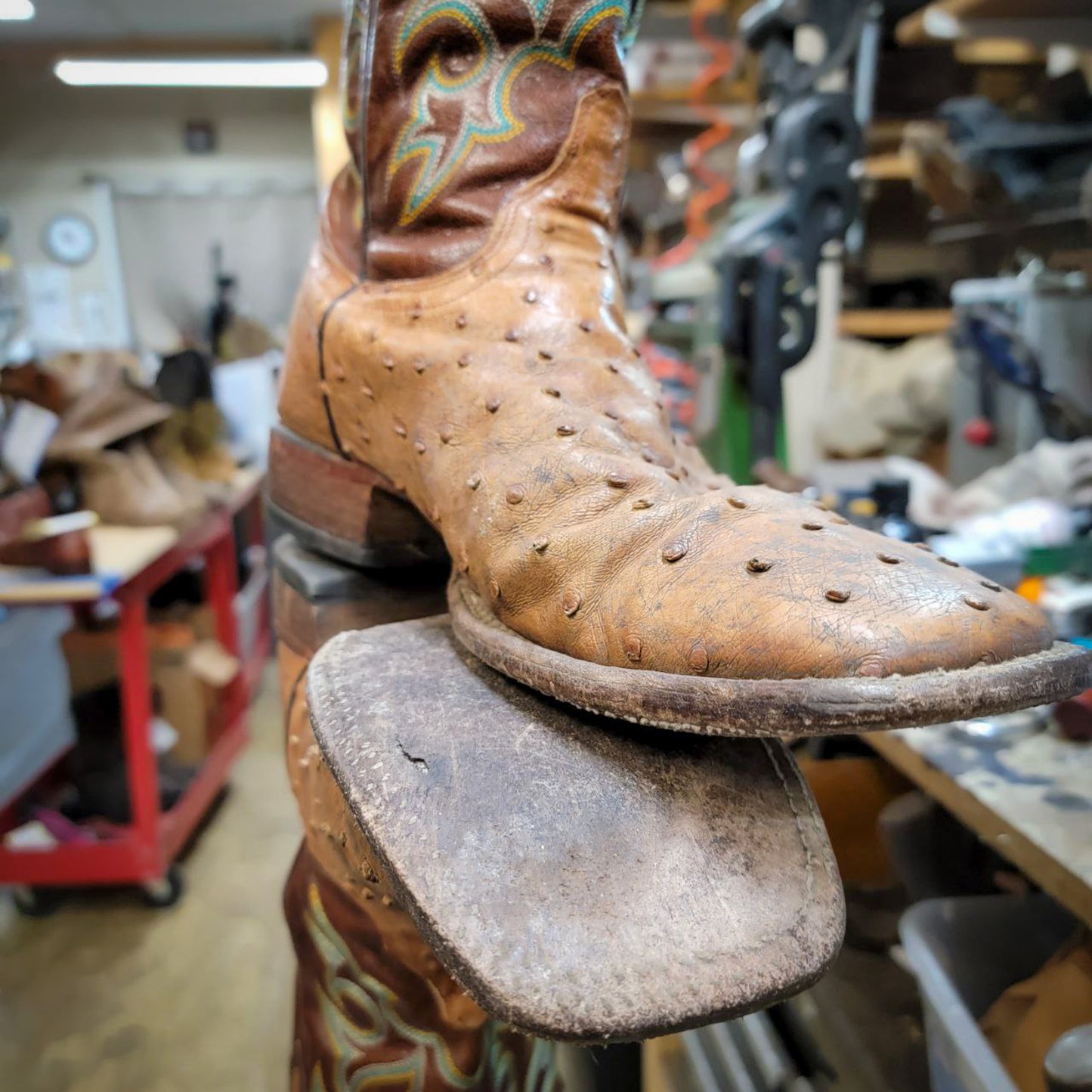 A pair of square toe Tony Lama Ostrich cowboy boots before being repaired with new leather soles at the cowboy boot repair center