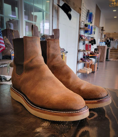 A pair of light brown Chelsea style boots after being repaired with new Vibram Wedge soles at The Boot Repair Center