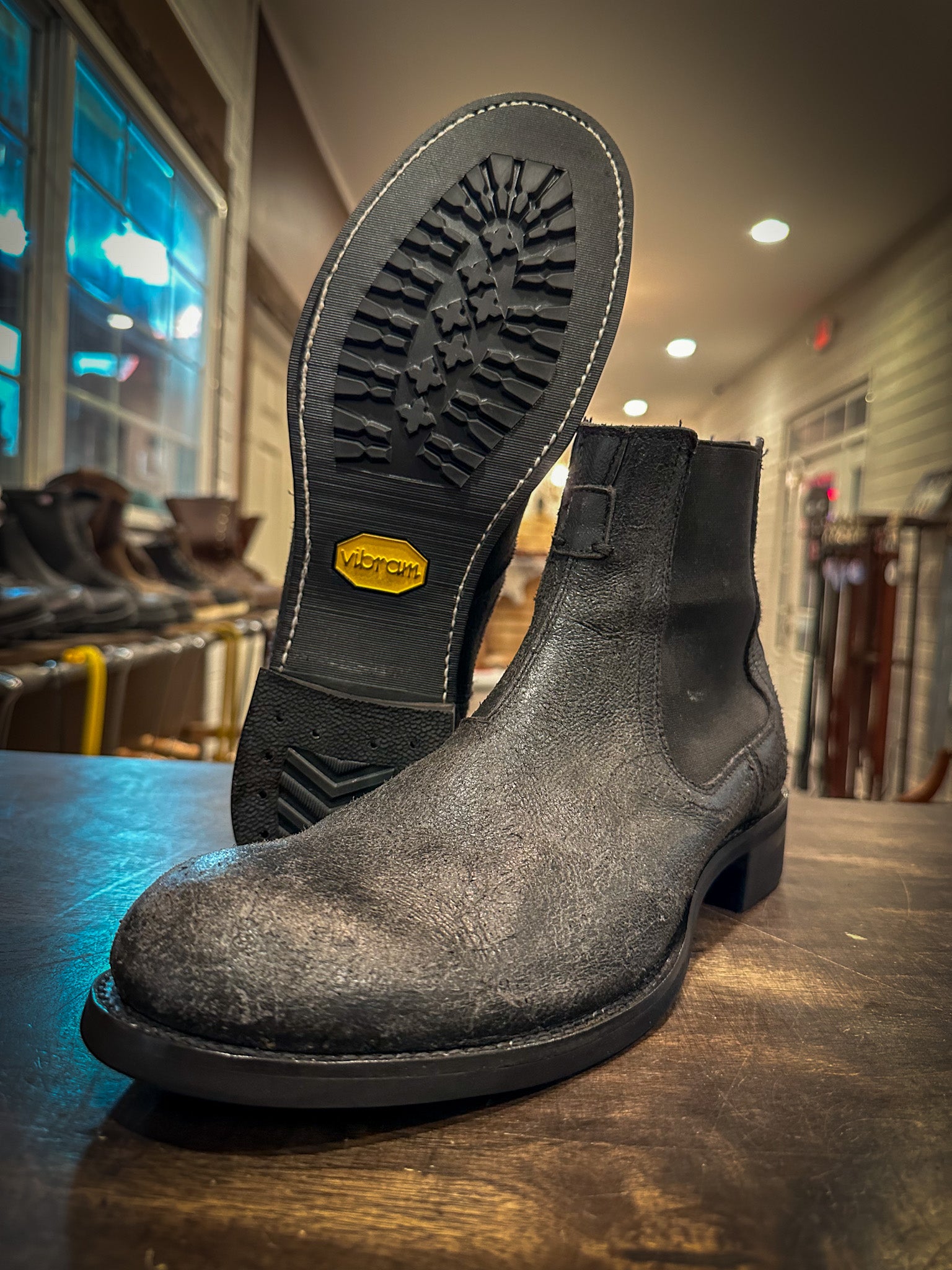 A pair of grey Chelsea Frye Boots repaired with the vibram 430 mini lug sole in black at the boot repair center